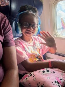 Smiling young girl wearing headphones on her first flight during Toby’s Dream Foundation trip.